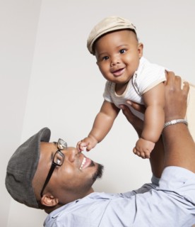 African American man lifting baby son into the air