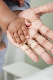 Close up of African American father and baby son's hands