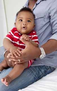 African American father holding baby son on lap