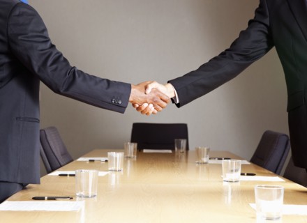Mixed race businessmen shaking hands in conference room