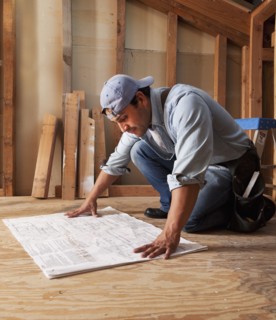 Hispanic construction worker looking at blueprints