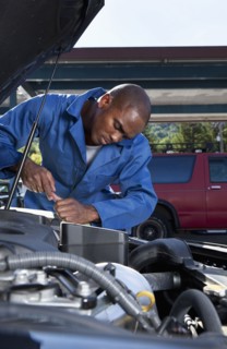 Black mechanic working on car engine