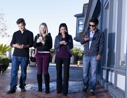 Friends using cell phones outdoors