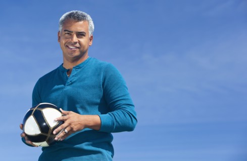 Mixed race man playing soccer outdoors