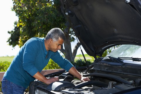 Mixed race man working on car engine