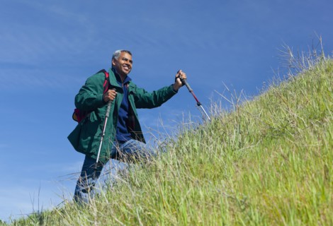 Mixed race man hiking on grassy hill