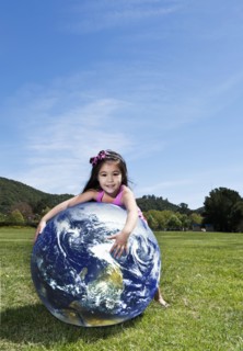 Mixed race girl playing with globe in park