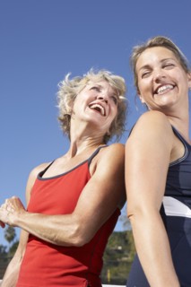 Women laughing back to back outdoors