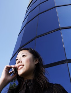 Chinese woman talking on cell phone by highrise