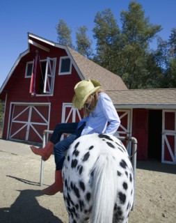 Mixed race girl riding horse on ranch