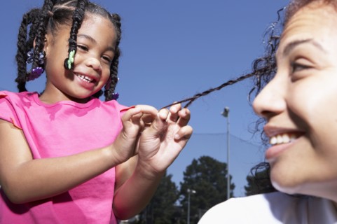 Mixed race girl braiding mother's hair