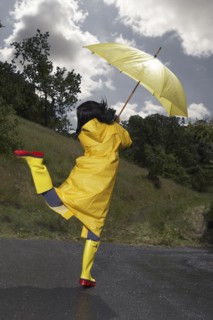 Indian woman wearing raincoat and rainboots with umbrella