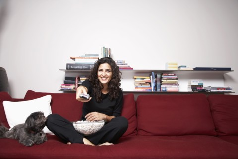Middle Eastern woman watching television on sofa