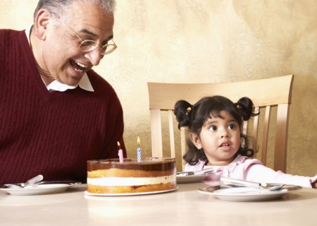 Senior Hispanic man and granddaughter celebrating birthday