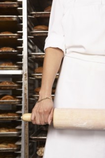 Hispanic baker holding rolling pin in bakery