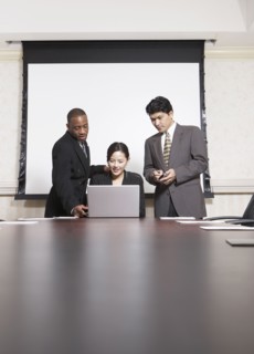 Business people using laptop at conference table