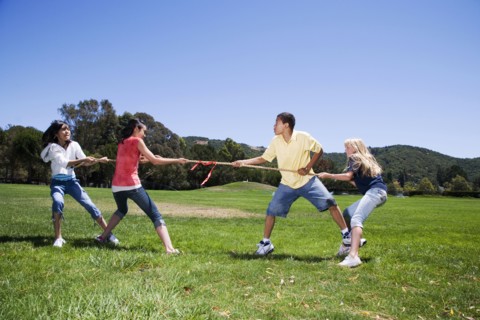 Children playing tug-of-war in field