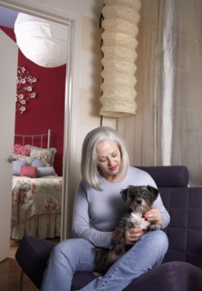 Senior Caucasian woman petting dog in armchair