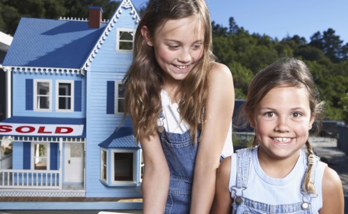 Mixed race girls smiling by doll house