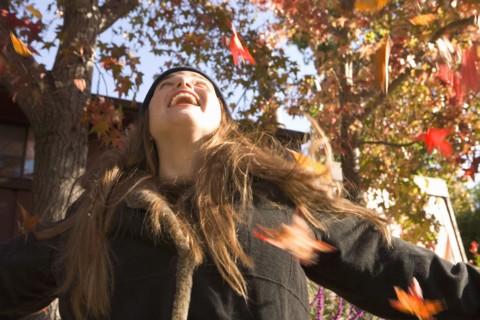 Caucasian woman playing in fall leaves