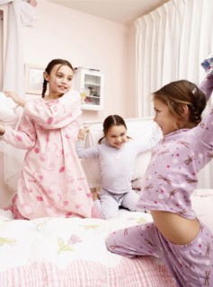 Mixed race girls having pillow fight on bed