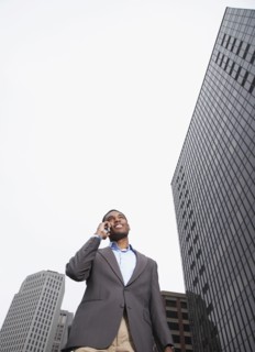 Mixed businessman talking on cell phone on city street