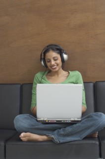 Middle Eastern woman typing on laptop and wearing headphones