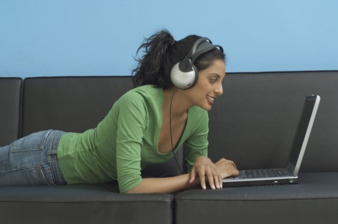 Middle Eastern woman looking at laptop and wearing headphones