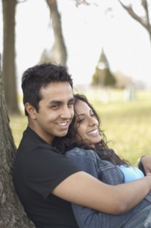Portrait of couple leaning against tree