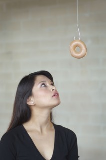 Asian woman looking at doughnut on hook