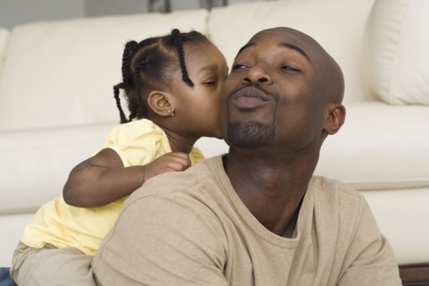 African girl kissing father's cheek