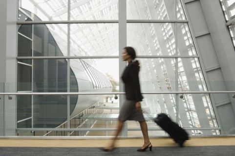 Hispanic businesswoman pulling suitcase