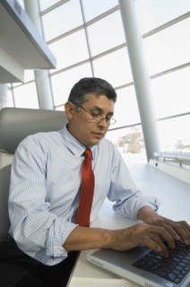 Hispanic businessman typing on laptop