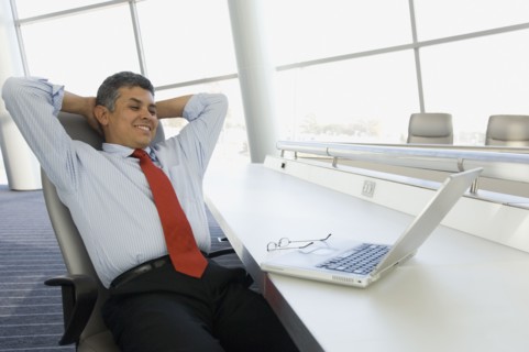 Hispanic businessman with hands behind head
