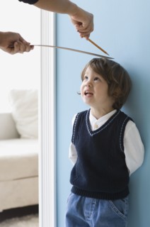 Asian boy having height measured on wall
