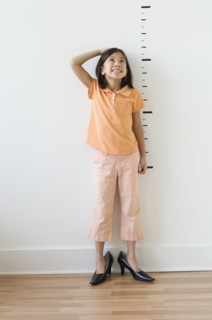 Asian girl wearing mother's shoes in front of height markers