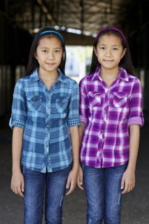 Asian twin girls smiling in barn