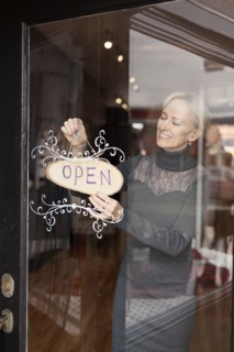 Caucasian small business owner hanging open sign on front door