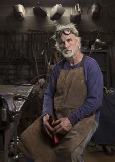Portrait of serious Caucasian blacksmith in workshop drinking beer
