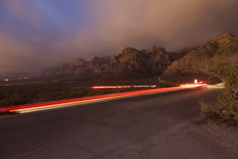 Curving light trails on street near mountain