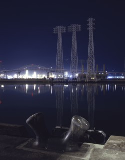Reflection of metal towers in harbor at night