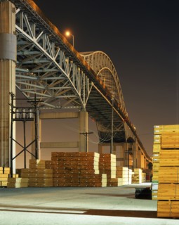 Piles of lumber under bridge at night