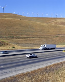 Cars and trucks driving on freeway near wind farm