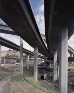 Trucks and cars driving under freeway overpass