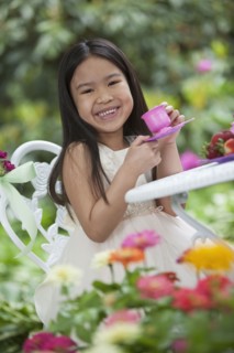 Mixed race girl having tea party in backyard