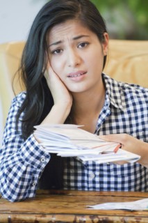 Woman sorting through bills on sofa