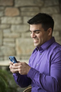 Hispanic businessman using cell phone indoors