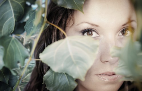 Native American woman peering through leaves