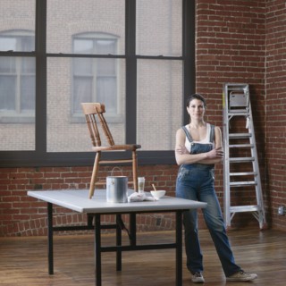 Mixed race woman painting chair in loft