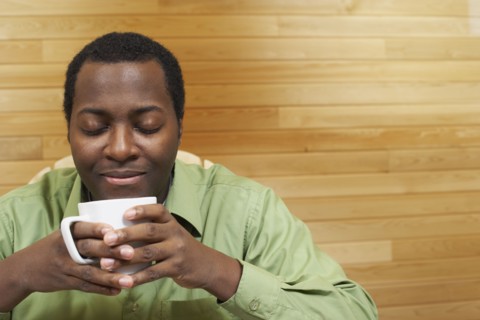 African man smelling cup of coffee